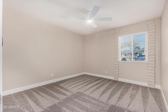 carpeted spare room with a ceiling fan and baseboards