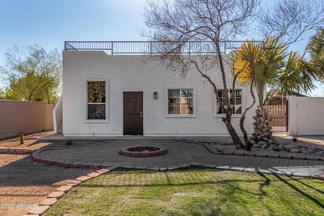 mediterranean / spanish home featuring a fire pit, a patio area, fence, and stucco siding