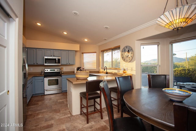 kitchen with stainless steel appliances, kitchen peninsula, a breakfast bar area, hanging light fixtures, and vaulted ceiling