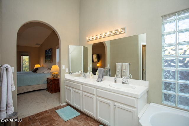 bathroom with vanity, a tub to relax in, and lofted ceiling