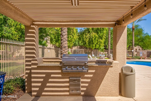 view of terrace featuring area for grilling, a community pool, and exterior kitchen