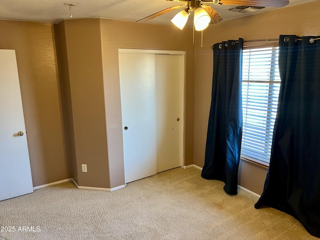 unfurnished bedroom with light colored carpet, ceiling fan, and a closet