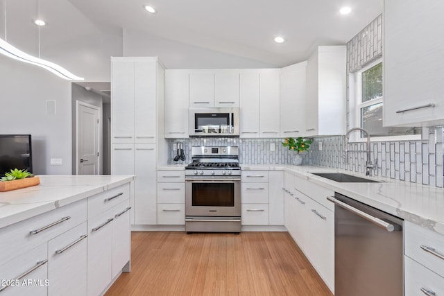 5210 W Jupiter Way N, Chandler, AZ 85226 - kitchen with appliances with stainless steel finishes, backsplash, white cabinets, light wood-type flooring, and vaulted ceiling
