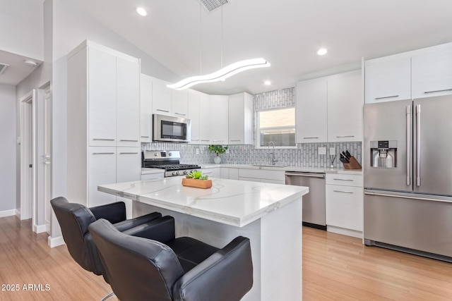 5210 W Jupiter Way N, Chandler, AZ 85226 - kitchen featuring appliances with stainless steel finishes, a kitchen breakfast bar, light wood finished floors, tasteful backsplash, and recessed lighting
