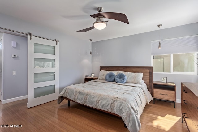 5210 W Jupiter Way N, Chandler, AZ 85226 - bedroom with light wood-style flooring, ceiling fan, and a barn door