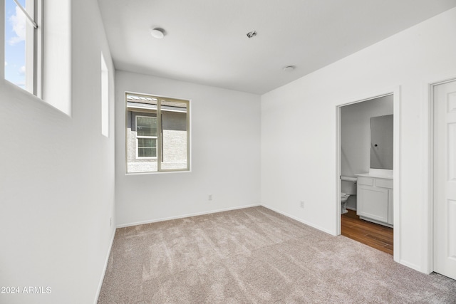 unfurnished bedroom with carpet, baseboards, and ensuite bathroom