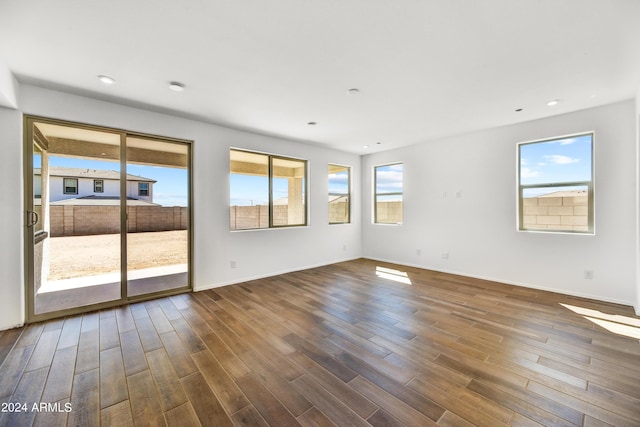 empty room with healthy amount of natural light, dark wood finished floors, baseboards, and recessed lighting