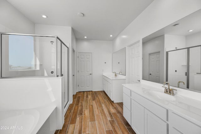 full bathroom featuring a stall shower, wood finished floors, two vanities, recessed lighting, and a bathtub