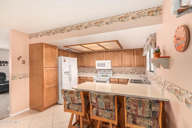 kitchen with kitchen peninsula, white appliances, a textured ceiling, sink, and light tile patterned floors