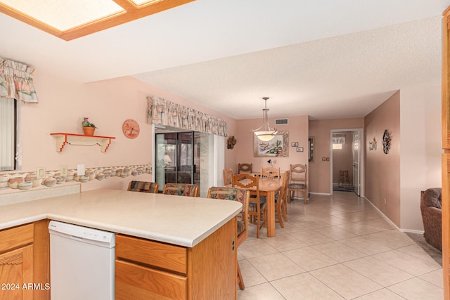 kitchen with kitchen peninsula, white dishwasher, pendant lighting, a textured ceiling, and light tile patterned floors