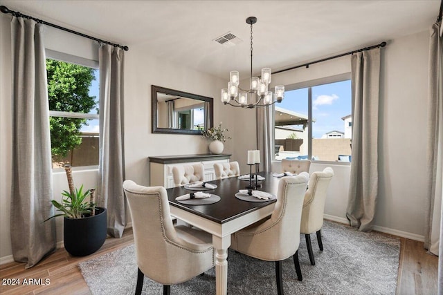 dining space with wood-type flooring, an inviting chandelier, and a healthy amount of sunlight