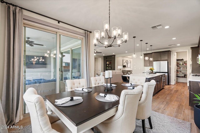 dining room featuring ceiling fan with notable chandelier, light hardwood / wood-style floors, and sink