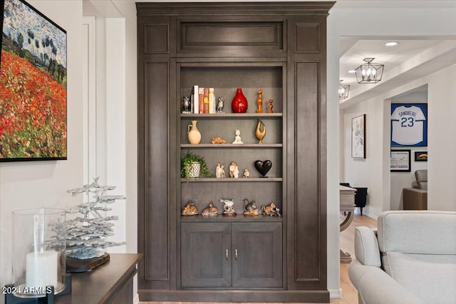 bar with dark brown cabinets, a chandelier, and wood-type flooring