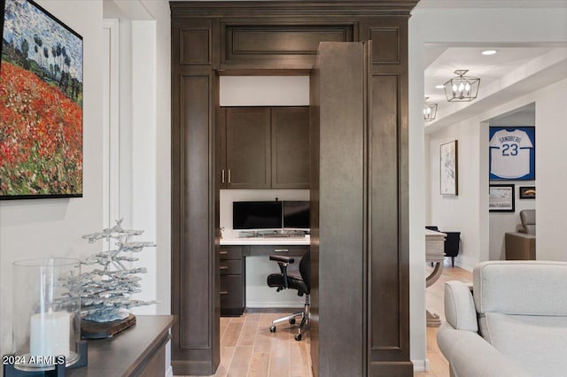 office area featuring a chandelier, light wood-type flooring, and built in desk