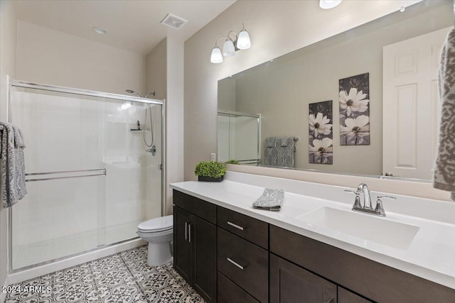 bathroom featuring tile patterned flooring, vanity, a shower with shower door, and toilet