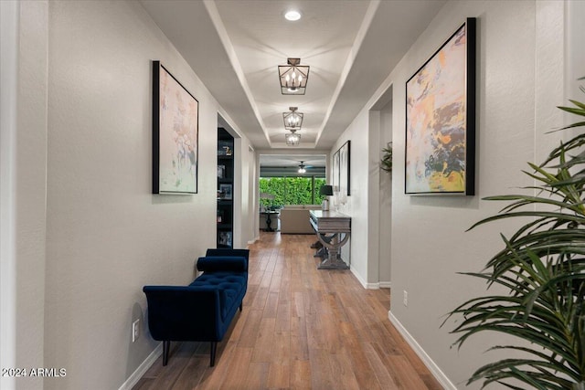 corridor with hardwood / wood-style floors and a chandelier