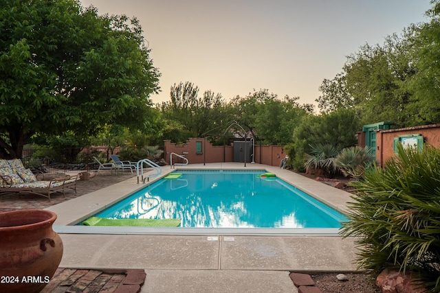 pool at dusk with a patio area