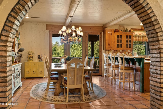 dining space with light tile patterned floors, a textured ceiling, and an inviting chandelier