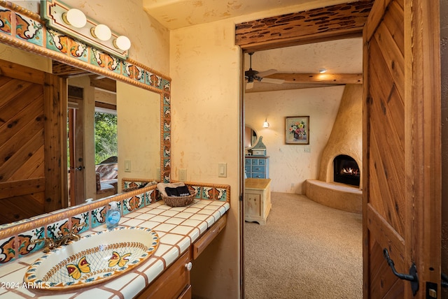 bathroom featuring vanity, a large fireplace, and ceiling fan