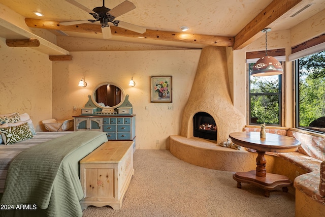 carpeted bedroom with ceiling fan, a large fireplace, and beamed ceiling