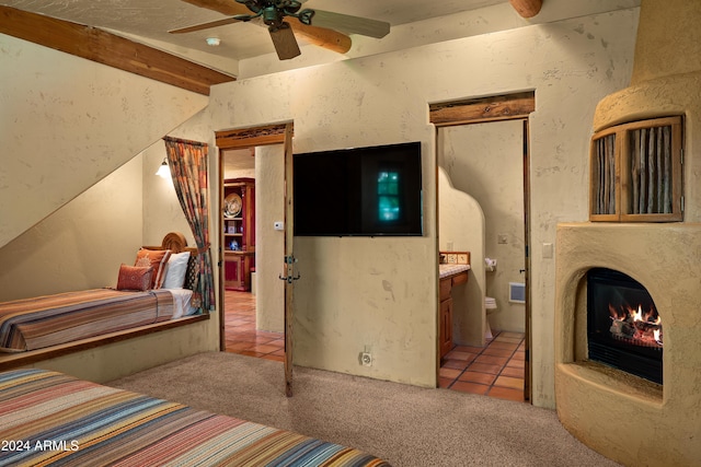 carpeted bedroom featuring beam ceiling, ensuite bath, and ceiling fan