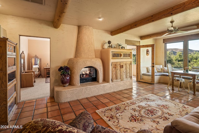 tiled living room with beamed ceiling, ceiling fan, and a fireplace