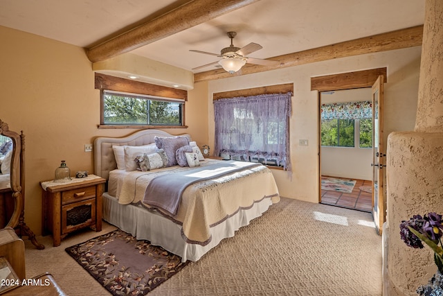 bedroom featuring beamed ceiling, ceiling fan, carpet floors, and multiple windows