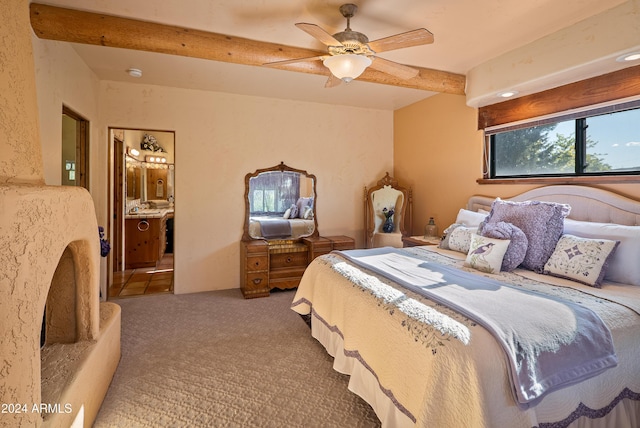 carpeted bedroom featuring beam ceiling, ensuite bath, and ceiling fan