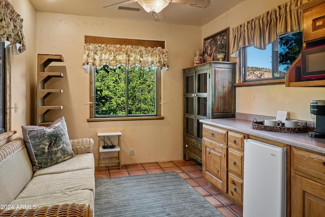 kitchen featuring ceiling fan, light tile patterned floors, a wealth of natural light, and fridge