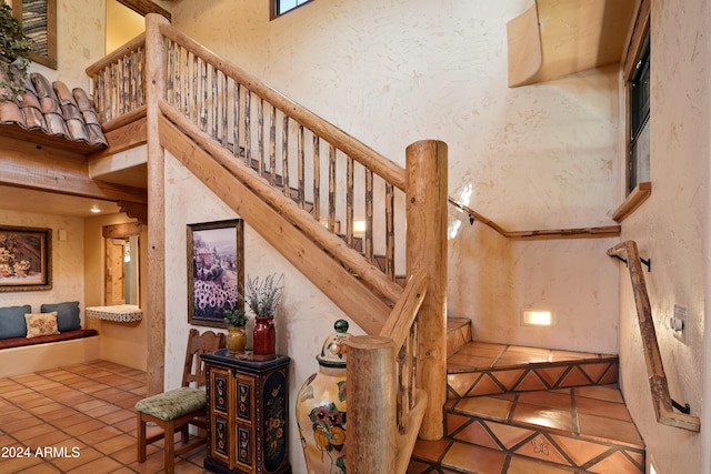 staircase featuring tile patterned flooring and a towering ceiling