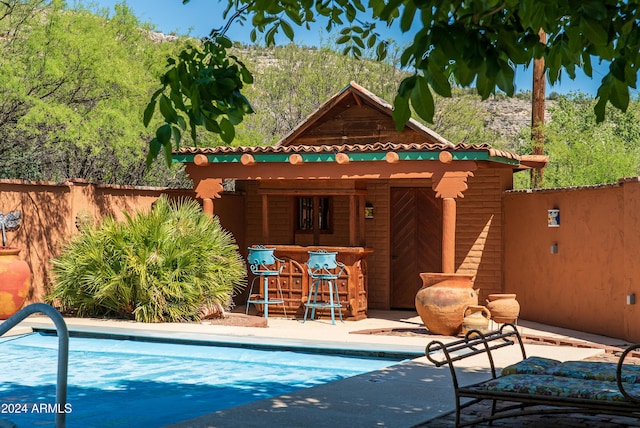 view of swimming pool featuring a patio area and a bar