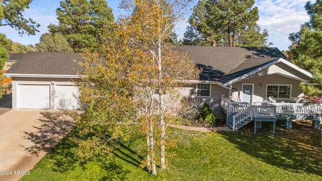 view of front of property featuring a wooden deck, a front lawn, and a garage