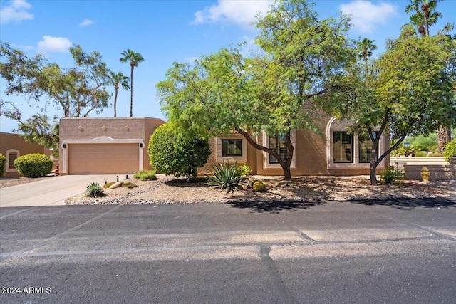 pueblo-style home with stucco siding, driveway, and an attached garage