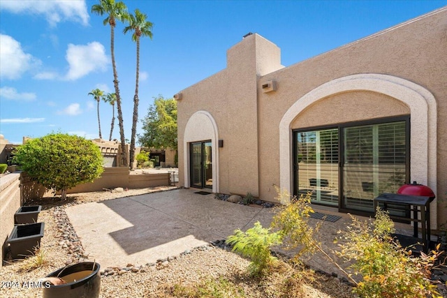 rear view of house with stucco siding, a patio, and fence