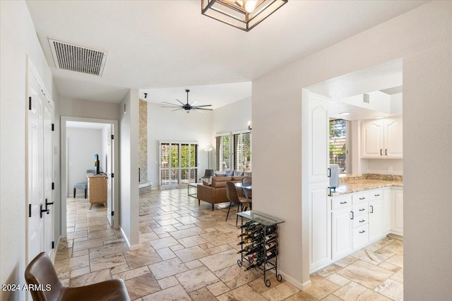 hallway with visible vents, baseboards, and stone tile flooring