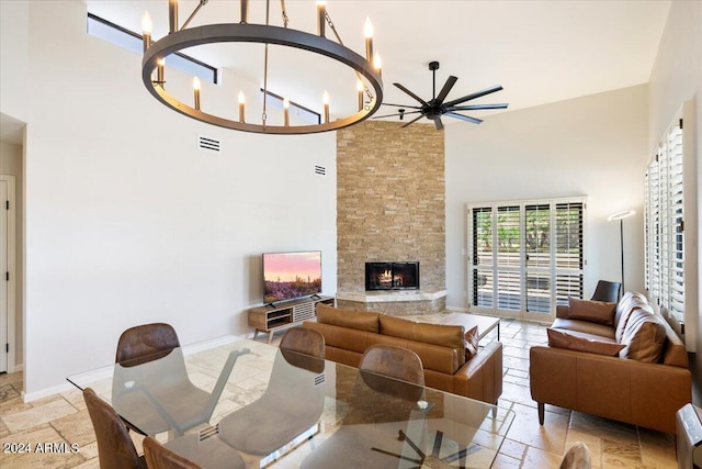 living room featuring stone tile floors, visible vents, a stone fireplace, and a high ceiling