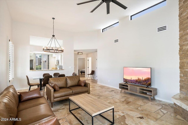 living area featuring baseboards, visible vents, a towering ceiling, and stone tile flooring