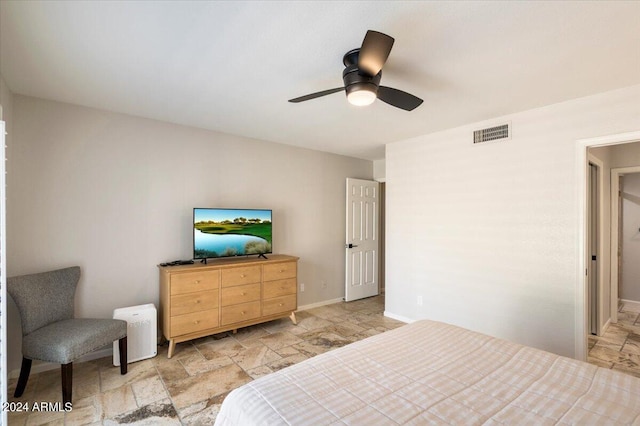 bedroom with visible vents, baseboards, stone tile floors, and a ceiling fan