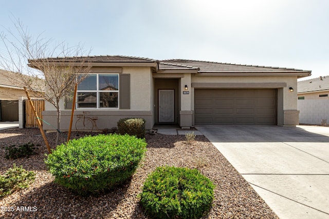 prairie-style house with stucco siding, fence, a garage, driveway, and a tiled roof