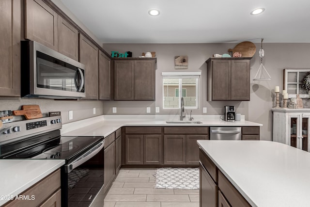 kitchen with stainless steel appliances, a sink, light countertops, and recessed lighting