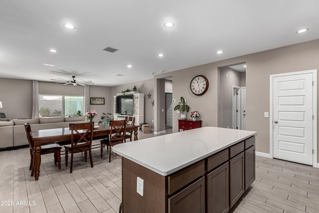 kitchen with wood finish floors, recessed lighting, visible vents, open floor plan, and a kitchen island