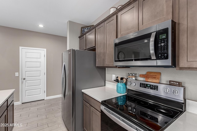 kitchen with recessed lighting, stainless steel appliances, baseboards, dark brown cabinets, and light countertops