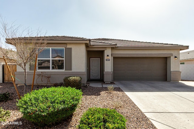 prairie-style home featuring a garage, driveway, a tile roof, fence, and stucco siding