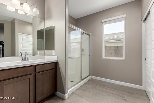 full bath with a stall shower, wood finished floors, vanity, and baseboards