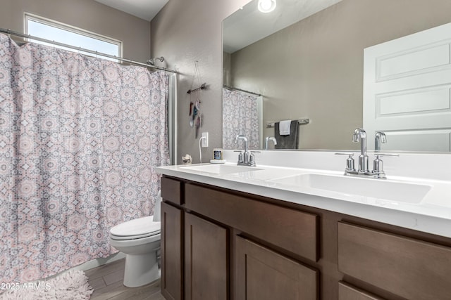 full bath with wood finished floors, a sink, toilet, and double vanity