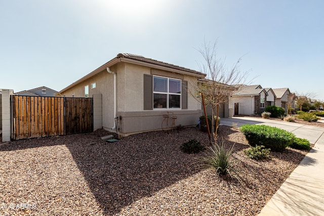 view of front facade with driveway, an attached garage, fence, and stucco siding