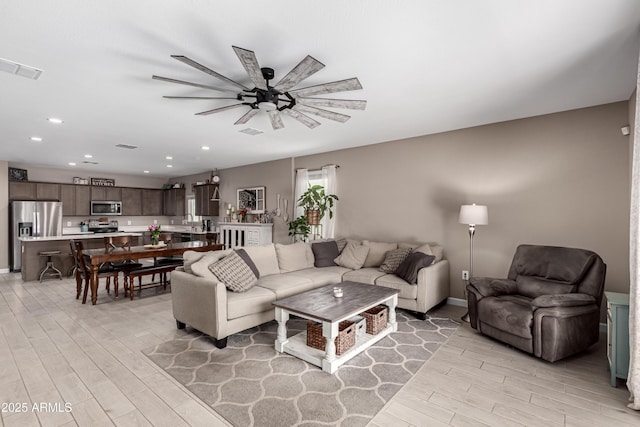 living room featuring ceiling fan, recessed lighting, visible vents, and light wood-style floors