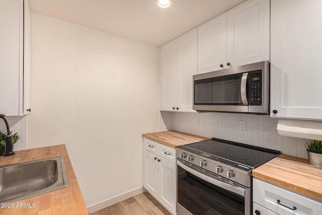 461 W Holmes Ave Unit 323, Mesa, AZ 85210 - kitchen featuring butcher block counters, appliances with stainless steel finishes, light wood finished floors, decorative backsplash, and white cabinetry