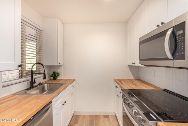 461 W Holmes Ave Unit 323, Mesa, AZ 85210 - kitchen featuring wood counters, appliances with stainless steel finishes, backsplash, light wood-style flooring, and white cabinetry