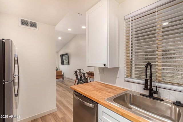461 W Holmes Ave Unit 323, Mesa, AZ 85210 - kitchen with appliances with stainless steel finishes, butcher block countertops, light wood finished floors, white cabinets, and recessed lighting